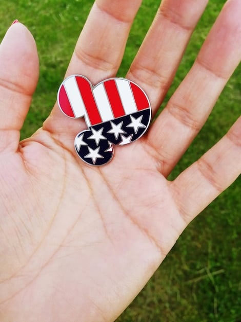 A close-up shot of two hands, one with an American flag pin and the other with a pin representing an Asian country flag, shaking hands over a document symbolizing a trade agreement. The background is blurred, focusing attention on the handshake and the document.